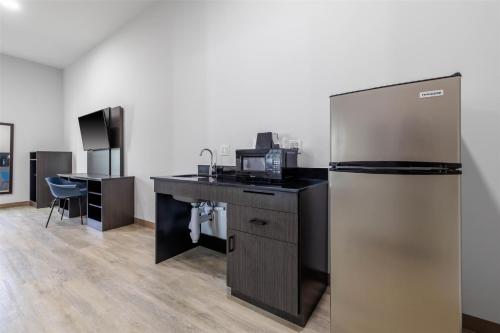 a kitchen with a refrigerator and a desk with a microwave at Studio 6 Gonzales, LA Baton Rouge Geismar Prairieville I 10 in Gonzales
