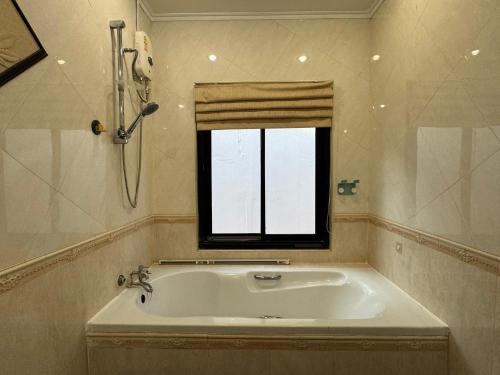 una bañera en un baño con ventana en B52 Pool Villa Pattaya, en Pattaya South