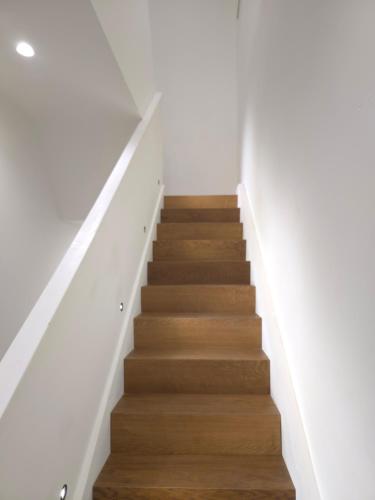 a staircase with wooden floors and white walls at Drymadhes Villas & appartments in Himare