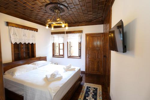 a bedroom with a bed with white sheets and a television at Oda e Gurit - Boutique Hotel in Berat