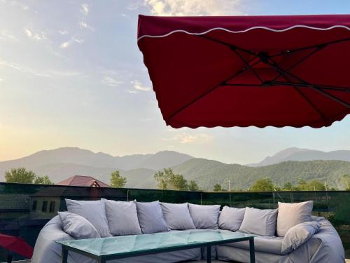 a red umbrella over a couch on a balcony at AZ Villa in Gabala in Gabala