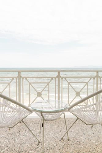 a table and a chair on the beach at Manda Ray Seafront Apartment Endless Blue View in Perea