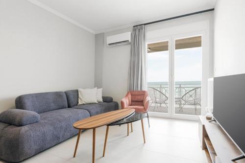 a living room with a couch and a table at Manda Ray Seafront Apartment Endless Blue View in Perea