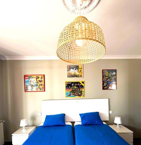 a bedroom with a blue bed and a chandelier at Delux LEIRIA Side in Leiria