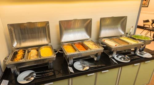 four trays of food on a counter in a kitchen at Hotel KK in Itu
