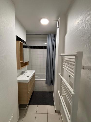une salle de bain avec un lavabo et une baignoire dans l'établissement Grand appartement à 3mn de la plage, à Saint-Nazaire