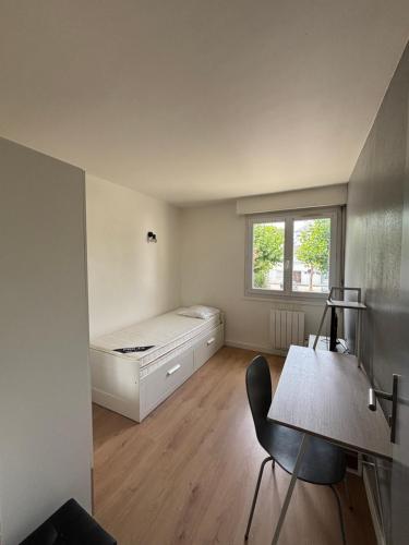 une chambre avec un lit, un bureau et une fenêtre dans l'établissement Grand appartement à 3mn de la plage, à Saint-Nazaire