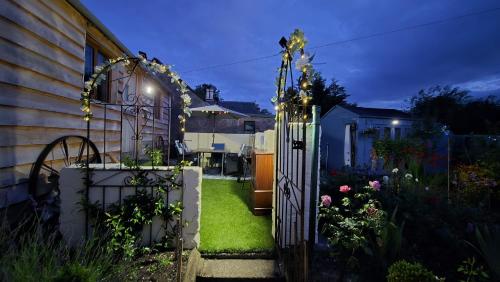 a garden with a gate with flowers and a house at Oor Hoose in Blairgowrie