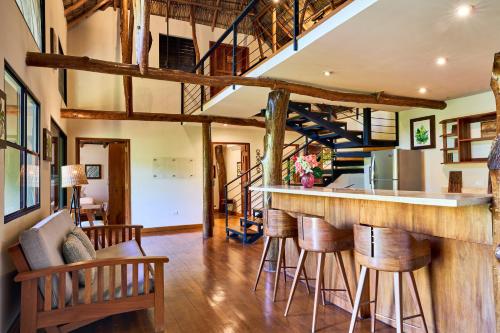 a kitchen with a bar with wooden stools at TreeCasa Hotel & Resort Nicaragua in San Juan del Sur