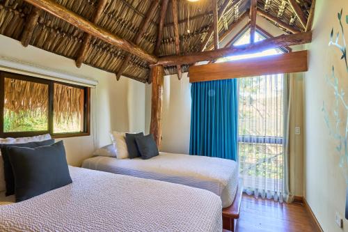 a bedroom with two beds and a large window at TreeCasa Hotel & Resort Nicaragua in San Juan del Sur