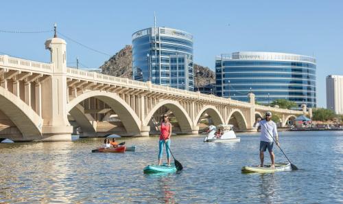 a group of people on paddle boards in the water near a bridge at Charming private guest house with pool in Tempe