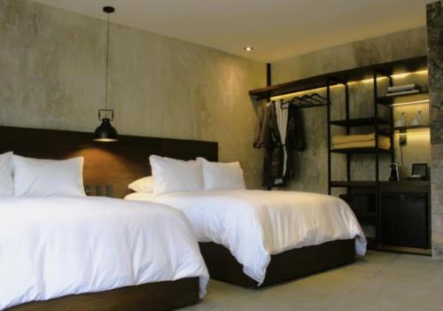 a bedroom with two beds with white sheets at Fisher´s House Hotel in Avándaro