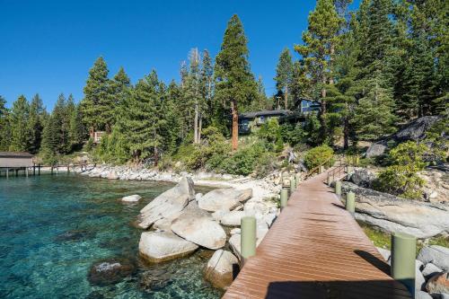 a wooden bridge over a river next to trees at McCown Lakefront By Hauserman Rentals in Tahoma
