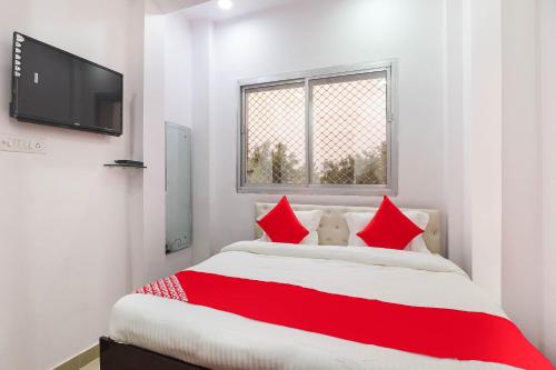 a bedroom with a bed with red pillows and a tv at Super HOTEL O CK INN in Charbagh