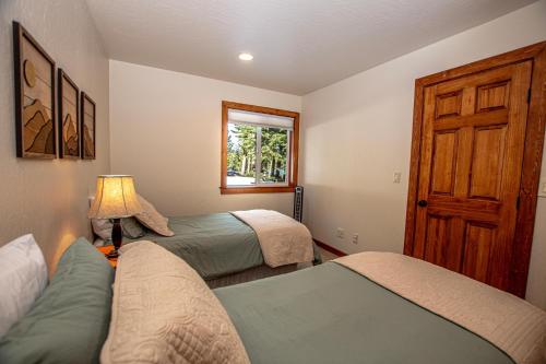 a bedroom with two beds and a lamp and a window at Tahoe Haven By Hauserman Rentals in Carnelian Bay