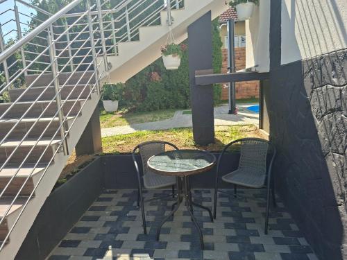 a table and two chairs on a patio with stairs at Gyöngyvirág Apartmanház in Zalakaros