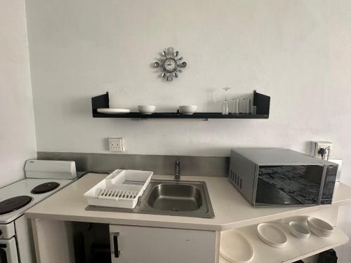 a kitchen counter with a sink and a microwave at Maboneng Studio Apartment in Johannesburg