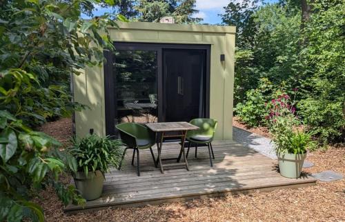 a small green shed with a table and chairs on a wooden deck at Logies Prinsewyk De Knipe/Oranjewoud in Bovenknijpe