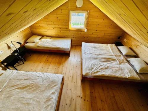 ミエレンコにあるHoliday Home in Mielenko near Seaside Beachのベッド2台と窓が備わる屋根裏部屋です。