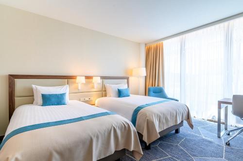 a hotel room with two beds and a desk at Crowne Plaza Maastricht by IHG in Maastricht