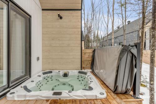 a jacuzzi tub on the deck of a house at Aigle Blanc Comfort & Nature Spa Fireplace & Furnished Terrace in Pont-Rouge