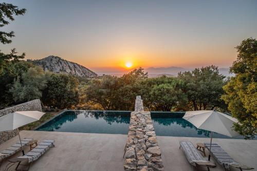 a swimming pool with a sunset in the background at Forest View Villas in Lagoúdi Zía