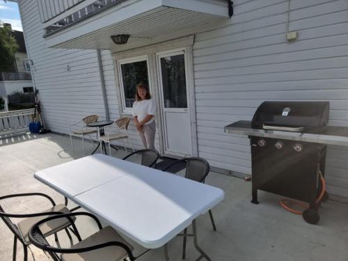 a woman standing on the porch of a house with a grill at Koselig Feriehus ved Kirkenes sentrum in Kirkenes