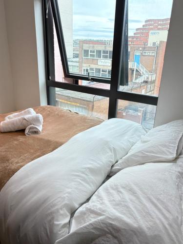 a bed with white sheets in front of a window at Central Sheffield Studio for 2 in Sheffield