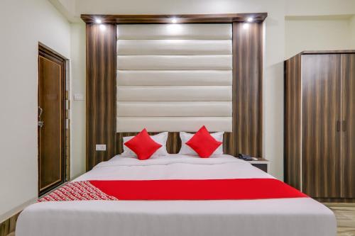 a bedroom with a large bed with red pillows at Hotel Navya Grand in Patna