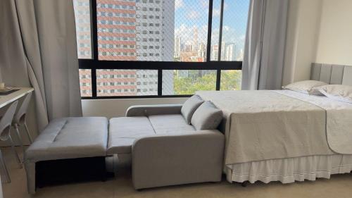 a bedroom with a bed and a couch and a large window at Max Derby - Studios no Centro do Recife por Yolo in Recife