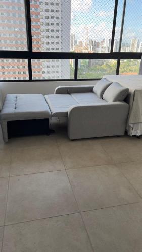 a couch in a room with a large window at Max Derby - Studios no Centro do Recife por Yolo in Recife