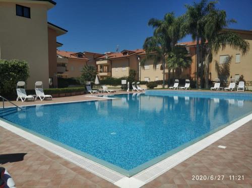 une grande piscine bleue avec des chaises et des bâtiments dans l'établissement way2 stay Italy, à Pizzo