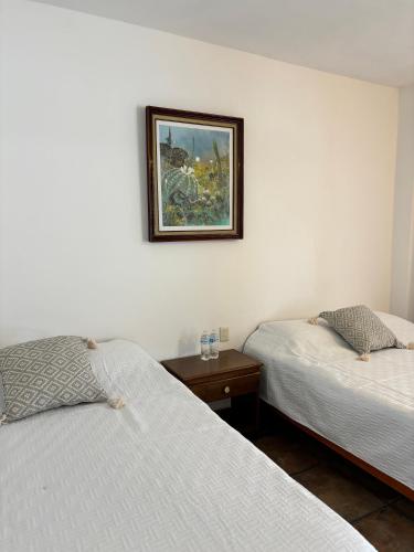 Teotitlán del ValleにあるHotel del Puebloのベッド2台が備わる部屋、壁に絵が飾られた部屋
