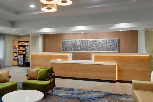 a lobby with a waiting area with green chairs and a desk at Fairfield Inn and Suites Charleston North/University Area in Charleston