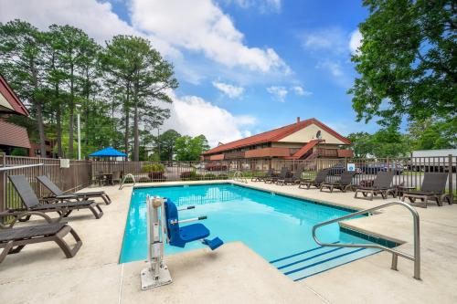 a swimming pool at a resort with lounge chairs at Red Roof Inn Virginia Beach in Virginia Beach