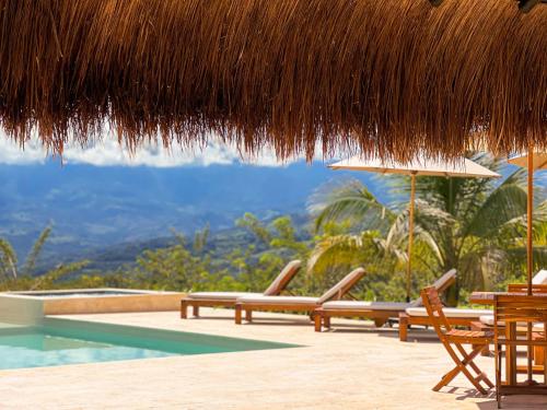 a resort with a pool and chairs and a straw umbrella at Fina Estampa Country Hotel by HMC - Mayores de 10 años - in Támesis