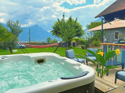 a hot tub in a yard with chairs and a hammock at gite de la chouette in Thyez
