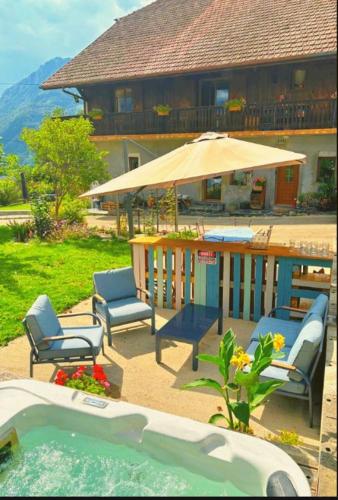 a pool with chairs and an umbrella next to a house at gite de la chouette in Thyez