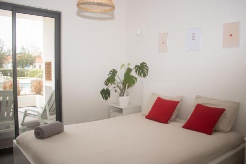 a bedroom with a bed with two red pillows at Apartament Alvor in Albur Village Lote A in Alvor