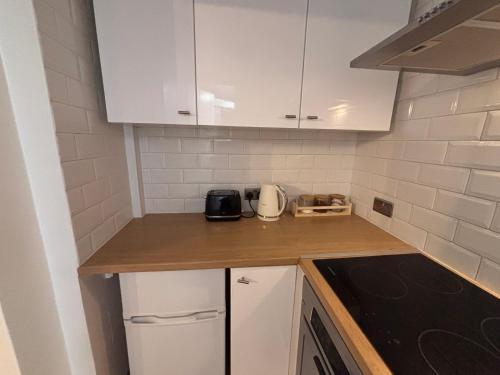 a kitchen with white cabinets and a counter top at Hidden Gem Apartment in Torquay