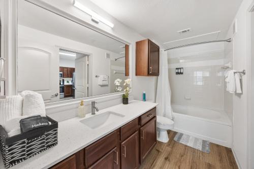 a bathroom with a sink and a toilet and a mirror at Brightshaven CoolSprings, Modern 1Bed with EV Parking in Frisco in Frisco