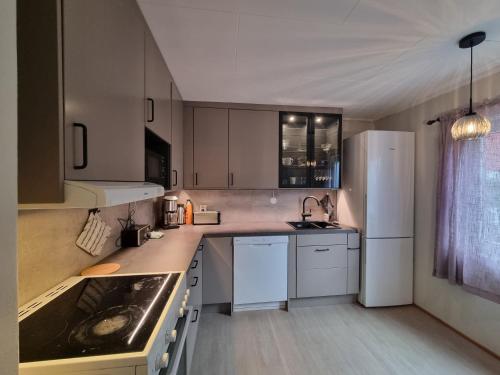 a kitchen with white cabinets and a white refrigerator at Koselig Feriehus ved Kirkenes sentrum in Kirkenes