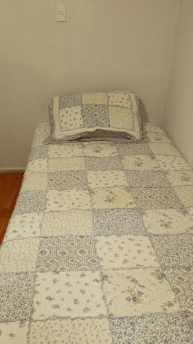 a bed with a quilt on it in a room at Luchito Borquez in La Serena