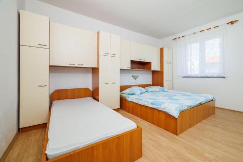 a bedroom with two beds and white cabinets at Apartments Anica J in Lopar