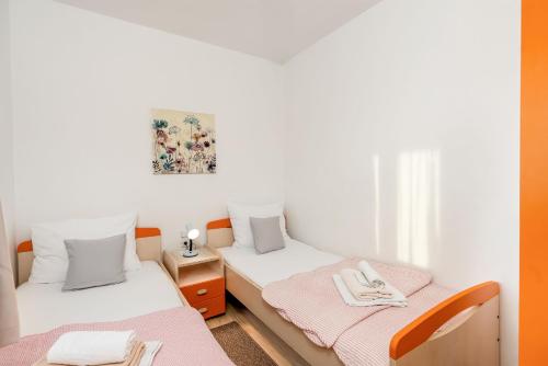 two beds in a room with white and orange at Apartment Diana in Povljana