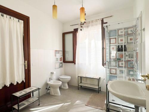 a white bathroom with a toilet and a sink at Casa Maristé in Favignana