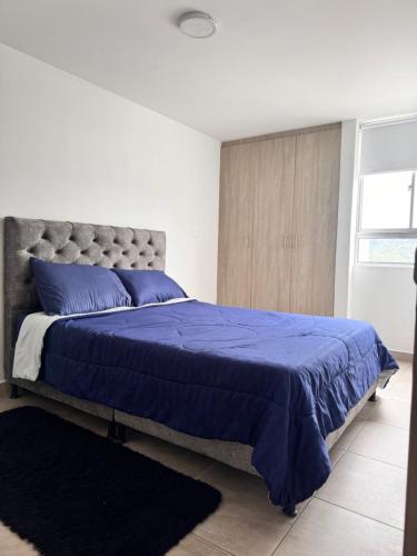 a bedroom with a bed with a blue comforter at Central, Universidades y Centro Comercial in Manizales