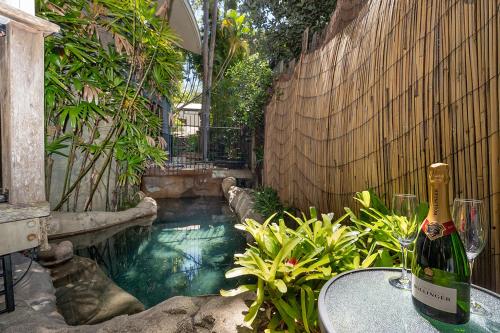 a bottle of wine sitting on a table next to a swimming pool at Little Cove 4BR Home, Pool, Pool table, Sleeps 16 in Noosa Heads