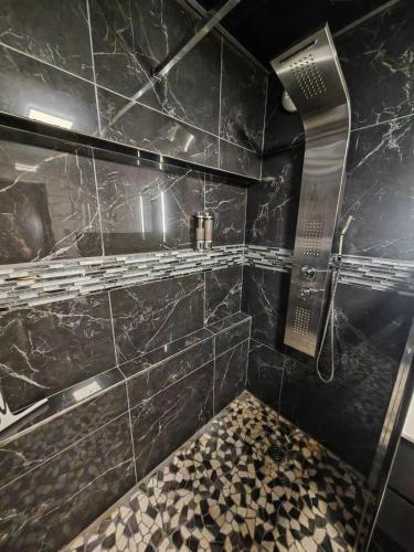 a bathroom with a shower with black marble tiles at L'Escale du Donon - Chambre Noire in Grandfontaine