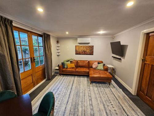 a living room with a brown leather couch and a tv at Gorgeous cottage near hospital, with garage in Wellington